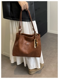 Detail of vintage brown tote bag with natural leather texture and boho beaded tassel