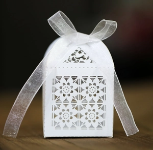 Macro view of white laser-cut floral candy box with elegant organza ribbon bow