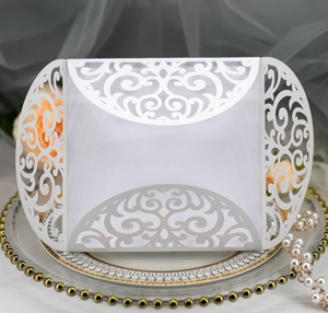 Close-up of white laser-cut floral wedding invitation on elegant decorative tray