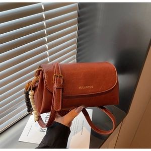 Detail of vintage brown crossbody bag with MULANKOU logo and decorative wooden beads