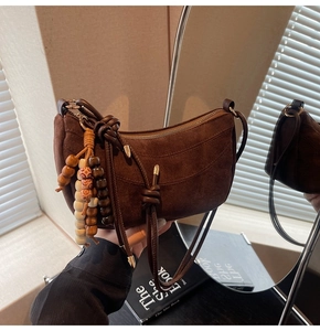 Detail of dark brown matte suede crescent bag featuring bohemian colorful beaded strap charms