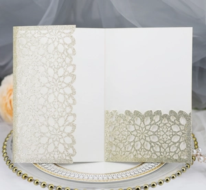 Detailed laser-cut floral pattern on cream-colored wedding invitation with gold glitter