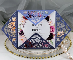 Detail of laser-cut navy blue rose wedding invitation on an elegant porcelain plate