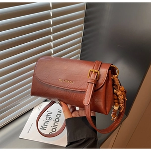 Detail of reddish-brown pleated leather texture and gold logo on vintage crossbody bag