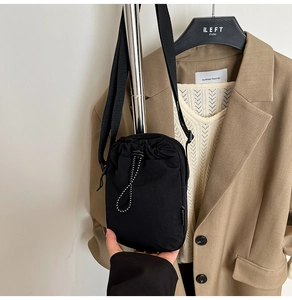 Minimalist black drawstring crossbody bag made of water-resistant nylon with fashion tag