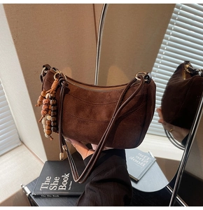 Detail of dark brown suede crescent bag with zipper and vintage wooden bead charm