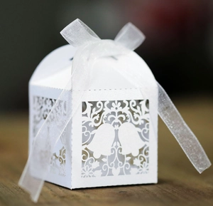 Detail of white laser-cut bell pattern gift box with white organza ribbon bow