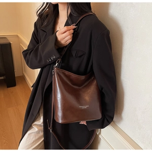 Détail d'un sac porté épaule en cuir huilé marron chocolat avec texte blanc mode
