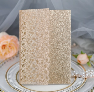 Macro view of champagne gold glitter laser-cut invitation card with lace floral details