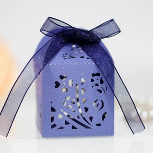 Detail of purple laser-cut candy box with floral patterns and a satin ribbon bow