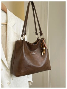 Detail of vintage brown tote bag with leather texture and bohemian beaded charm accessory