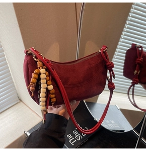 Detail of burgundy frosted leather dumpling bag with beaded fringe tassel and zipper