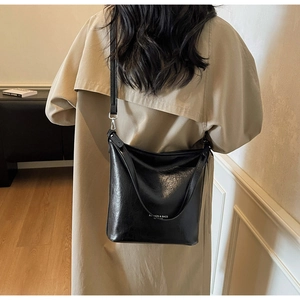 Détail d'un sac cabas noir brillant avec inscription et bandoulière réglable