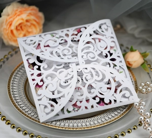 Laser-cut white wedding invitation card with floral insert and elegant scrollwork details