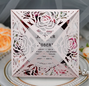 Macro shot of laser-cut rose hollow design on pearl pink wedding invitations with inner card