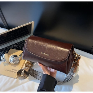 Detail of vintage brown leather bag with geometric pattern wide strap and gold logo