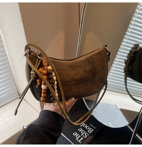 Detail of dark brown matte suede hobo bag with wooden bead charm and long shoulder straps