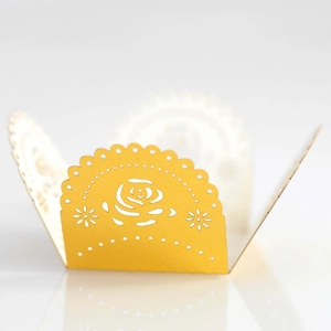 Macro detail of laser-cut rose patterns on a bright yellow paper wedding favor box