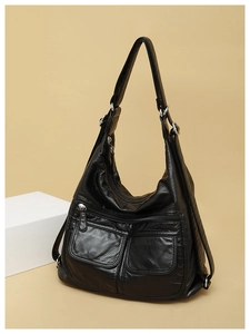Detail of black soft leather shoulder bag with multiple zippers and silver hardware