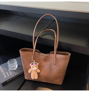Deep brown faux leather tote bag detail with lychee texture and plush bear pendant