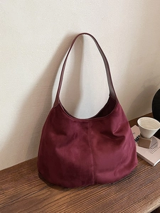 Vintage burgundy suede hobo tote bag for women shown on a wooden table setup