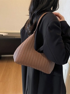 Borsa hobo marrone in pelle intrecciata indossata da una modella con stile minimalista