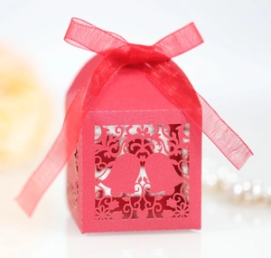 Detail of red laser-cut favor box with Christmas bell patterns and ribbon bow