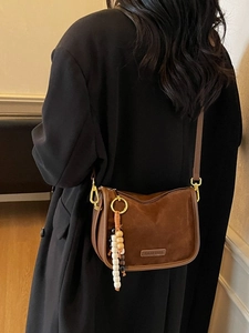 Sac à bandoulière vintage marron en daim givré avec perles en bois porté par un mannequin