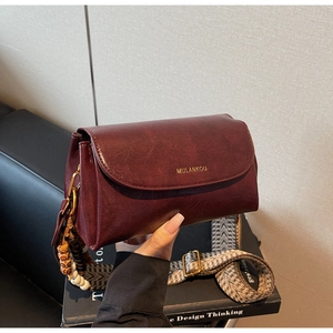 Detail view of burgundy matte leather bag with ethnic tassel and geometric strap
