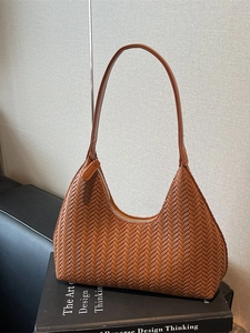 Borsa a spalla hobo intrecciata marrone appoggiata su un libro per un look di classe