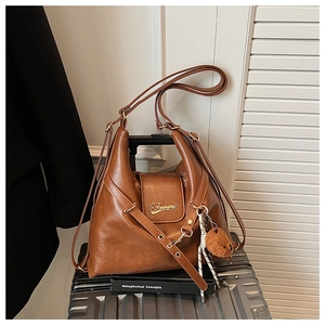Détail d'un sac cabas marron vintage avec pendentif ours sur une valise rayée