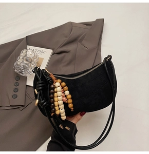 Detail of black suede crescent bag featuring a stylish ethnic beaded tassel accessory