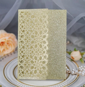 Close-up of glitter champagne gold laser-cut floral invitation on elegant porcelain tray