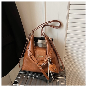 Gros plan du sac cabas vintage marron avec logo doré et breloque ours en peluche
