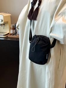 Minimalist black drawstring crossbody mobile phone bag with adjustable strap and fashion label