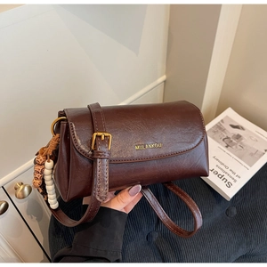 Detailed close-up of dark brown vintage PU leather crossbody bag with golden buckle and charms