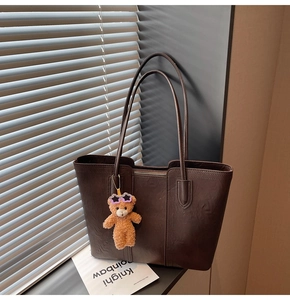 Detail of coffee brown large tote bag with cute plush bear charm on slender straps