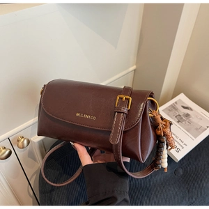 Detail of dark brown leather crossbody bag with ethnic wood bead tassel and gold logo