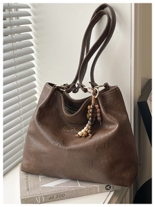 Detailed macro view of vintage brown leather tote bag with wooden bead charm ornament