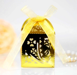 Macro view of laser-cut gold gift box with floral heart patterns and yellow ribbon