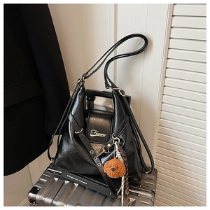 Gros plan du sac cabas en cuir noir sur valise avec charm d'ours et logo doré