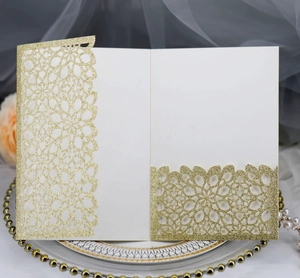 Detail of laser-cut gold glitter invitation cover with intricate floral lace texture