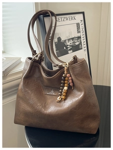 Detailed view of vintage dark brown tote bag with leather texture and bead charm