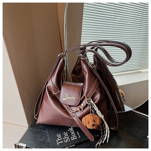 Détail d'un sac cabas vintage marron foncé avec logo métallique et breloque chien peluche