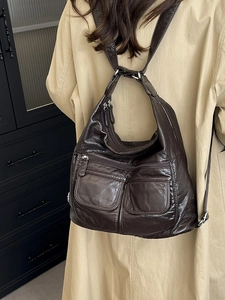 Deep brown multifunctional travel backpack in soft PU leather worn with casual trench coat