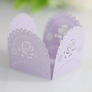 Close-up of lavender laser-cut paper cupcake wrappers with elegant rose lace patterns