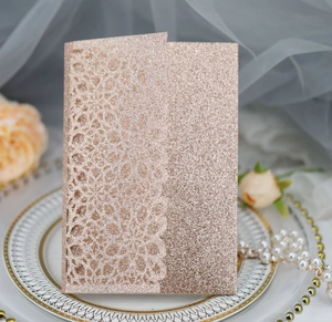 Detail showing the intricate laser-cut lace pattern on rose gold glitter invitation card