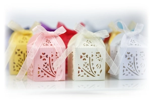 Laser-cut wedding favor boxes with floral patterns and delicate organza ribbons