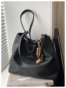 Close-up of black retro tote bag with textured faux leather and colorful beaded tassel