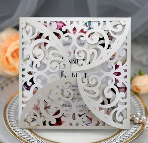 Close-up of laser-cut wedding invitation card with floral insert and pearl accents
